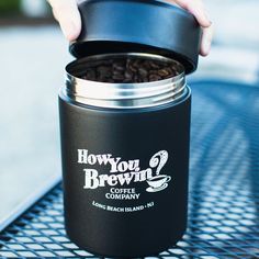 a person holding a coffee canister full of coffee beans