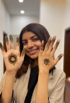 a woman holding up her hands with hendi tattoos on it's palms and smiling