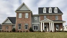 a large brick house sitting on top of a lush green field