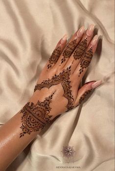 a woman's hand with henna on it laying on top of a bed