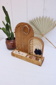 a wooden box with jewelry in it sitting next to a cactus