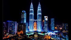 an aerial view of the city at night with tall buildings lit up in blue and white