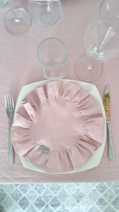 there is a pink place setting on the table with silverware and utensils