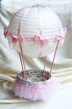 a white paper ballon with pink bows on it's top sitting in a basket