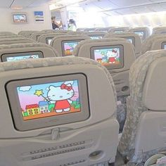 an airplane with hello kitty on it's screen in the back row, while people watch from their seats