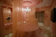 a fancy bedroom with pink walls and chandelier hanging from the ceiling, along with a round bed