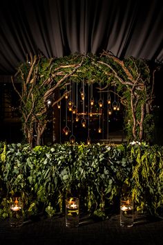 a wedding arch with candles and greenery on the sides at night time in front of an outdoor venue