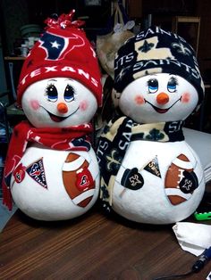 two snowmen wearing hats and scarves sitting next to each other on a table