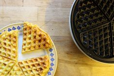 two waffles cut in half on a plate next to a pancake maker