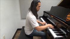 a man sitting at a piano with long hair