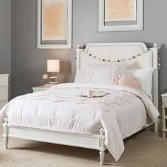 a bedroom with gray walls, white furniture and pictures on the wall above the bed