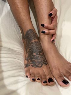 two women with black nail polishes on their feet and one has a dragon tattoo