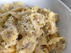 a white bowl filled with pasta covered in cheese