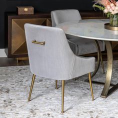 a dining room table with two chairs and a vase filled with flowers on the side