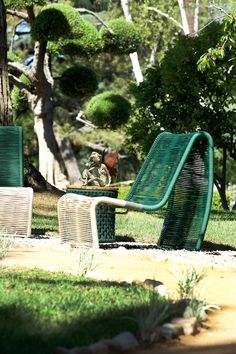 two lawn chairs sitting on top of a grass covered field next to a park bench