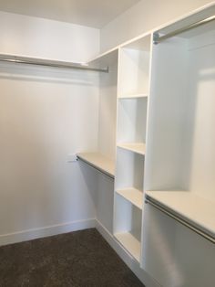 an empty white closet with shelves and hanging bars on the wall next to carpeted floor