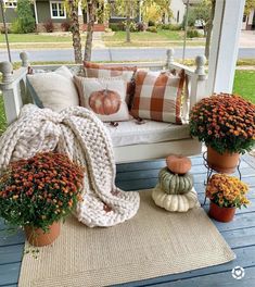 a porch swing with pumpkins and flowers on it