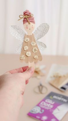 a hand holding up a paper angel with flowers on it