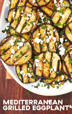 grilled eggplant with feta cheese and herbs on a white platter