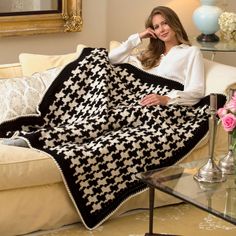 a woman sitting on a couch with a black and white blanket