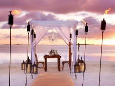 a gazebo set up on the beach for a wedding ceremony with candles and flowers