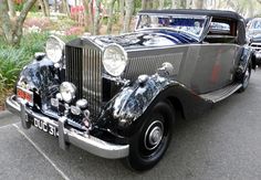 an old black car is parked on the street