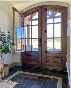 a large wooden door sitting inside of a house next to a plant on the floor