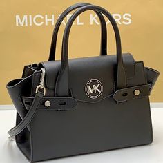 Michael Kors Carmen Medium Flap Saffiano Leather Belted Satchel Black Color Designed In A Classic Trapeze Shape, Our Carmen Satchel Is Equal Parts Refined And Practical. This Version Is Crafted From Faux Leather With Gilded Hardware For A Luxe Finish, While A Detachable Crossbody Strap Provides Added Versatility. Its Belted Side Gussets Can Be Adjusted And Open To A Pocketed Interior Sized To Store The Essentials. Details Satchel Black Color Silver -Tone Hardware 11"W X 7.75"H X 5"D Handle Drop: Michael Kors Black Satchel With Adjustable Strap, Luxury Michael Kors Satchel With Leather Handles, Michael Kors Black Satchel Bag, Michael Kors Black Satchel With Detachable Handle, Michael Kors Black Bag With Detachable Handle, Michael Kors Black, Wallet Bag, Michael Kors Bag, Leather Belt