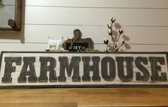 a sign that says farm house on top of a wooden table next to a vase with flowers