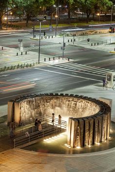 people are standing at the top of a circular structure on a city street with traffic lights