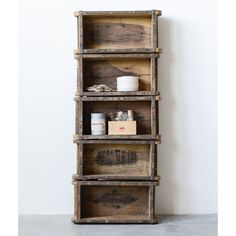 an old wooden shelf with jars and containers on the bottom, in front of a white wall