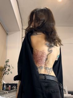 a woman with tattoos on her back standing next to a bed