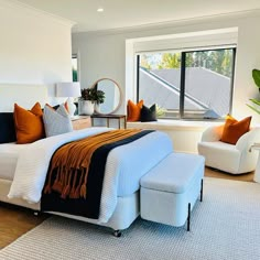 a bedroom with a bed, chair and ottoman