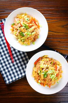 two white bowls filled with food on top of a wooden table