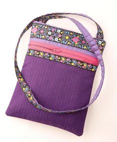 a purple purse with flowers on the side and zippered closures is sitting on a white surface