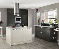 a modern kitchen with grey cabinets and white counter tops, stainless steel appliances and an island in the middle