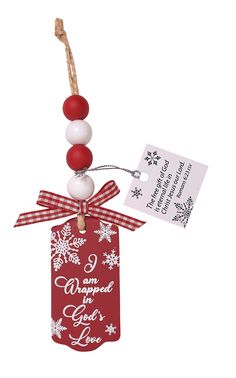 a red and white christmas ornament hanging from a wooden stick with a tag attached to it