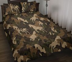 a bed with camouflage sheets and pillows on top of wooden flooring next to a window