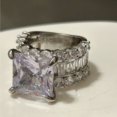 an engagement ring set with a princess cut diamond surrounded by baguetts of diamonds