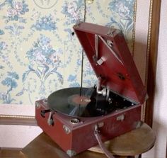 an old record player sitting on top of a wooden table next to a floral wallpaper