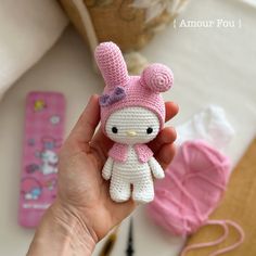 a hand holding a small crocheted hello kitty doll