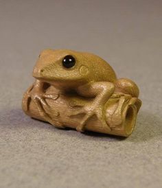 a toy frog sitting on top of a piece of wood