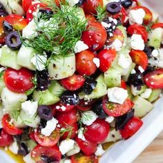 a salad with cucumbers, tomatoes, olives and feta cheese on it