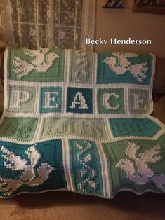 a crocheted blanket with the words peace written on it in white and green