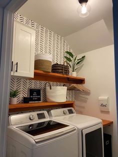 a washer and dryer in a small room with open shelving on the wall