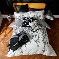 a bed with black and white comforter on top of it in front of a wooden floor