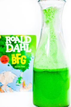 a bottle filled with green liquid next to a book