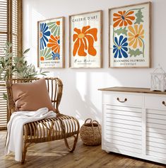 three framed art prints hang on the wall above a wooden chair in a white room