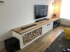 a flat screen tv sitting on top of a wooden shelf next to a wall mounted speaker