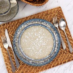 an empty plate on a place mat with silverware next to it and a basket